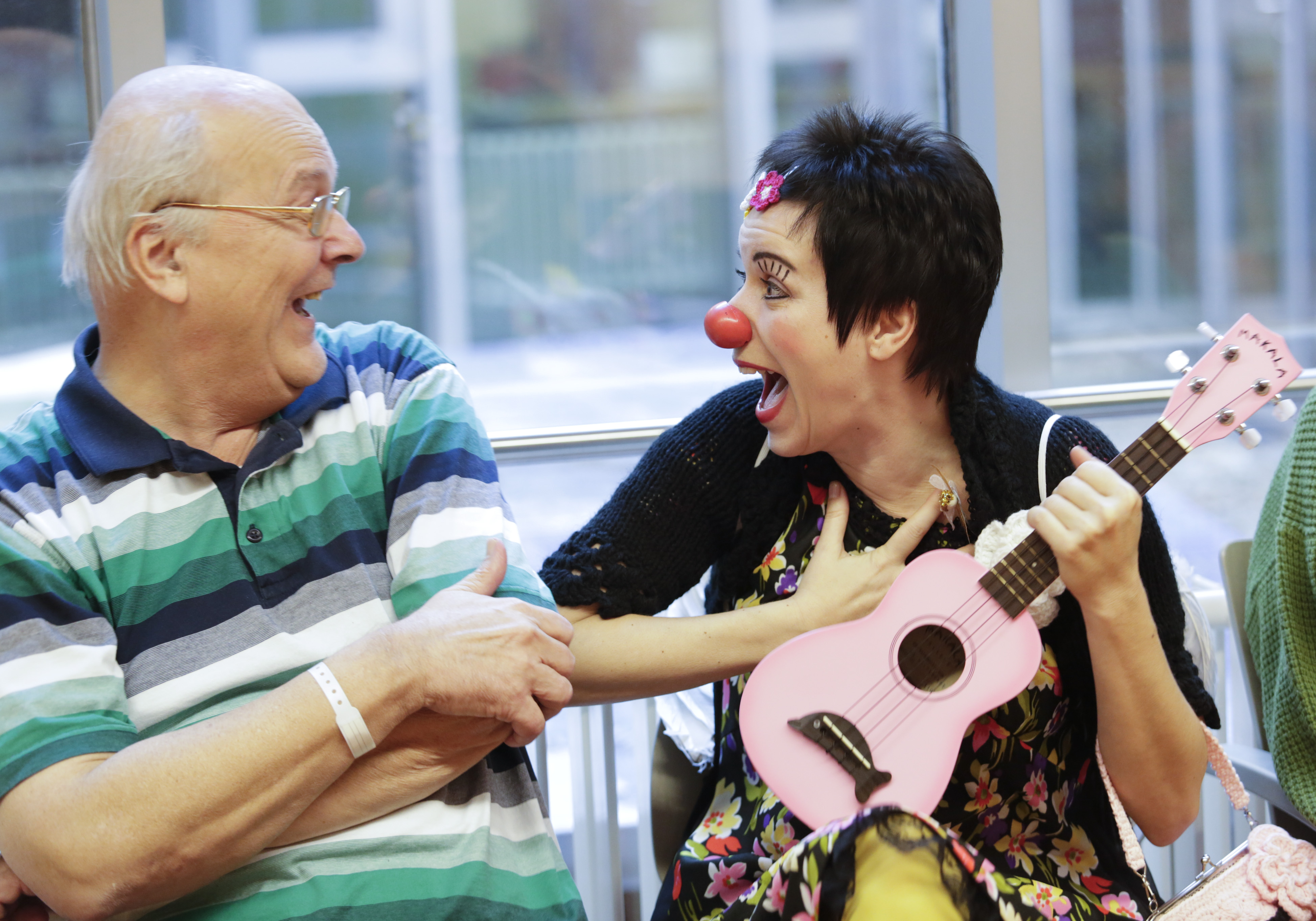 old man laughing with female clown holding guitar 