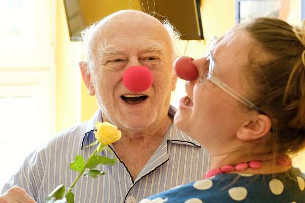Old man laughing with female clown