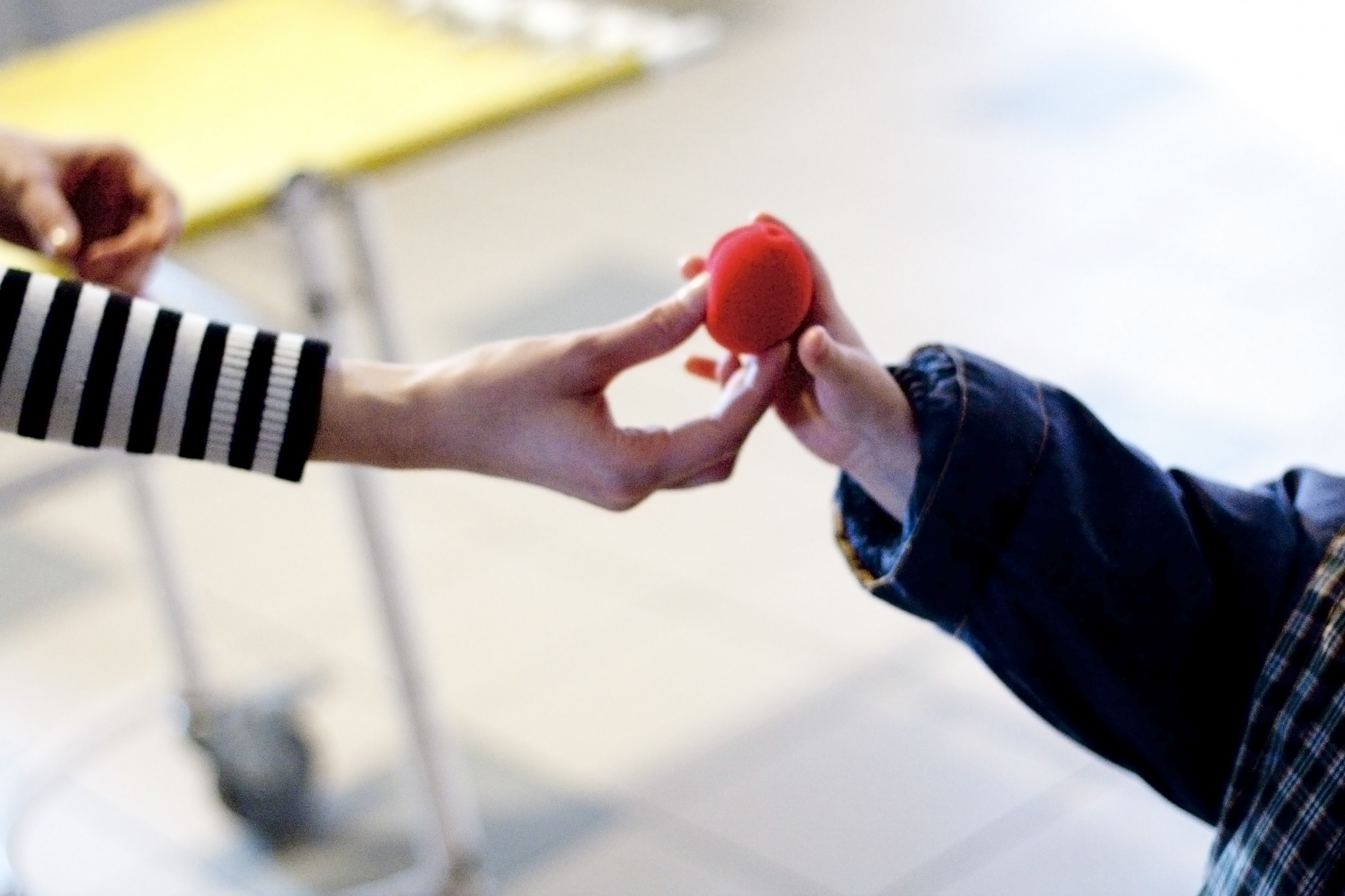 Adult hand giving red nose to child hand